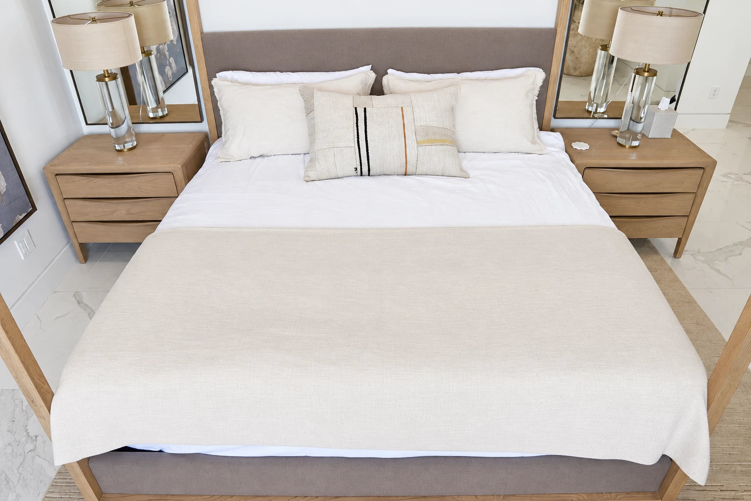 A neatly made shared bed with neutral bedding and pillows