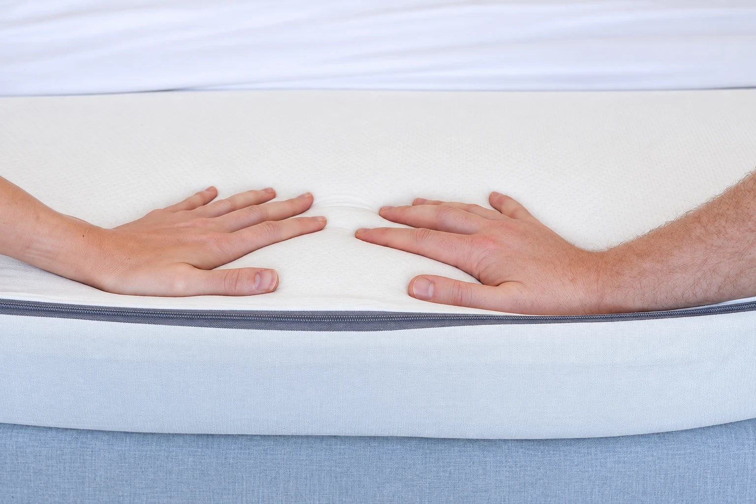 Two people pressing the continuous comfort layer of the Comfy Couples topper